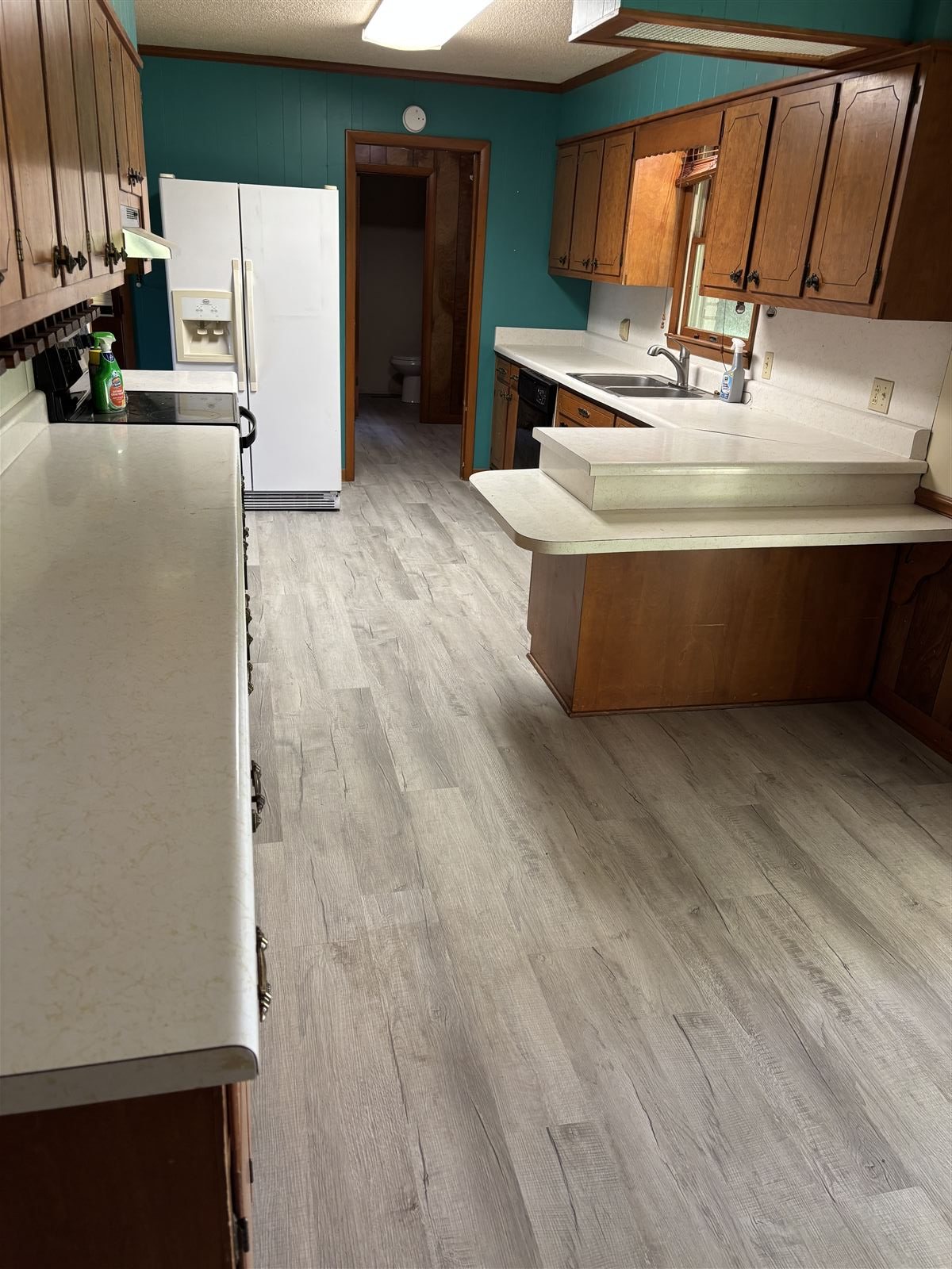 Kitchen remodel with new flooring, wood cabinets, and updated counters