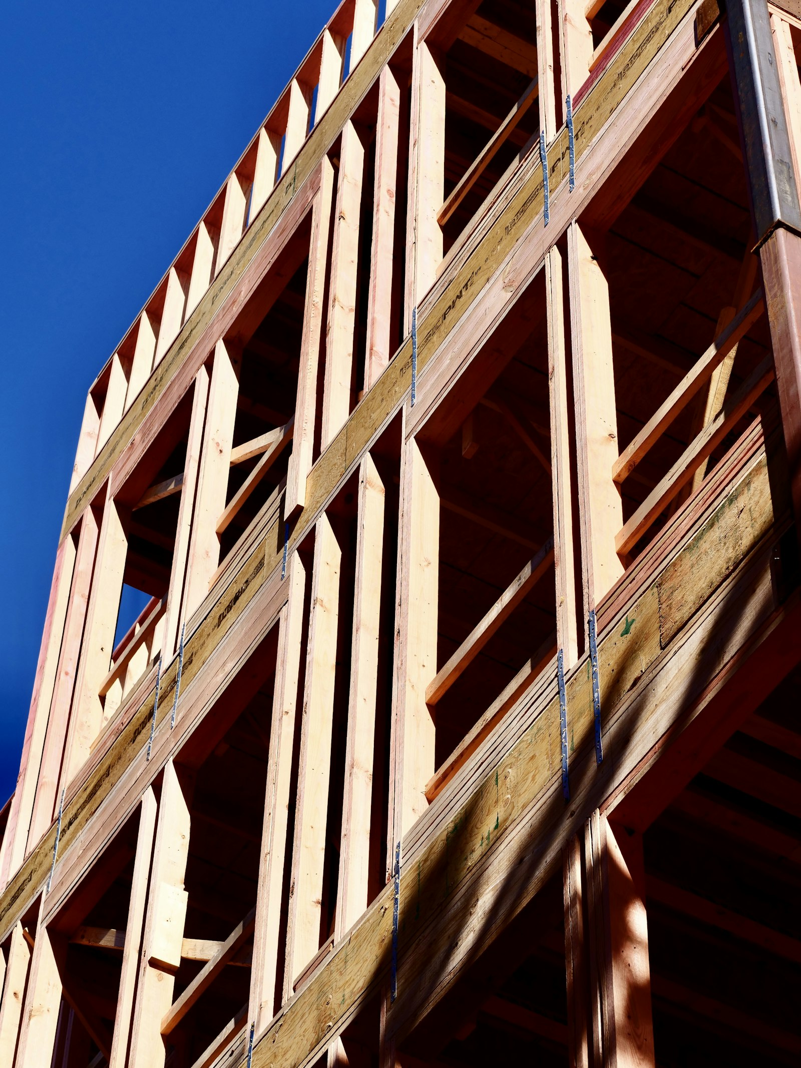Wood structural framing of a house under construction against a blue sky